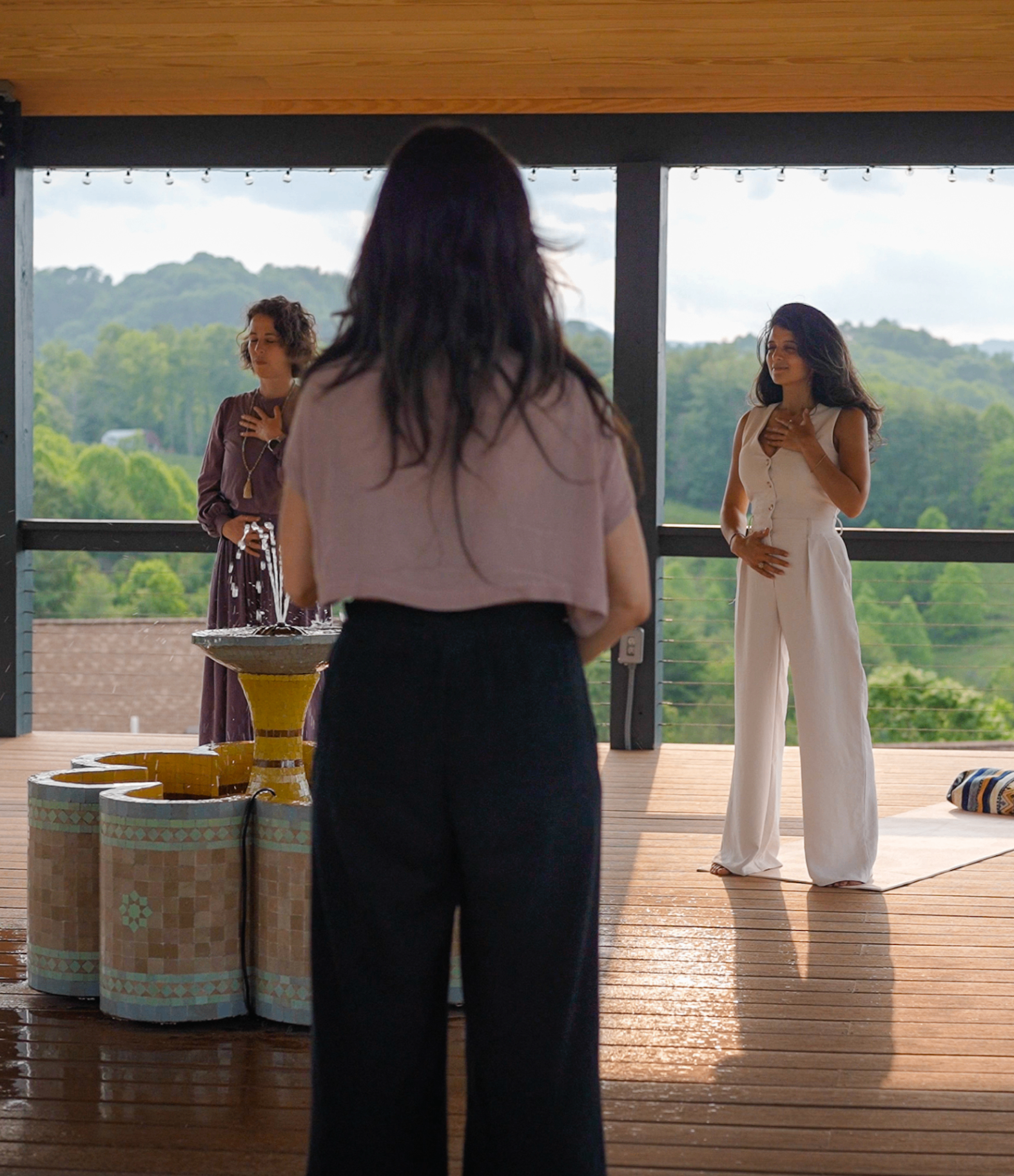 Three women in ceremony on the Sultana pavilion, hands on hearts, Blue Ridge behind