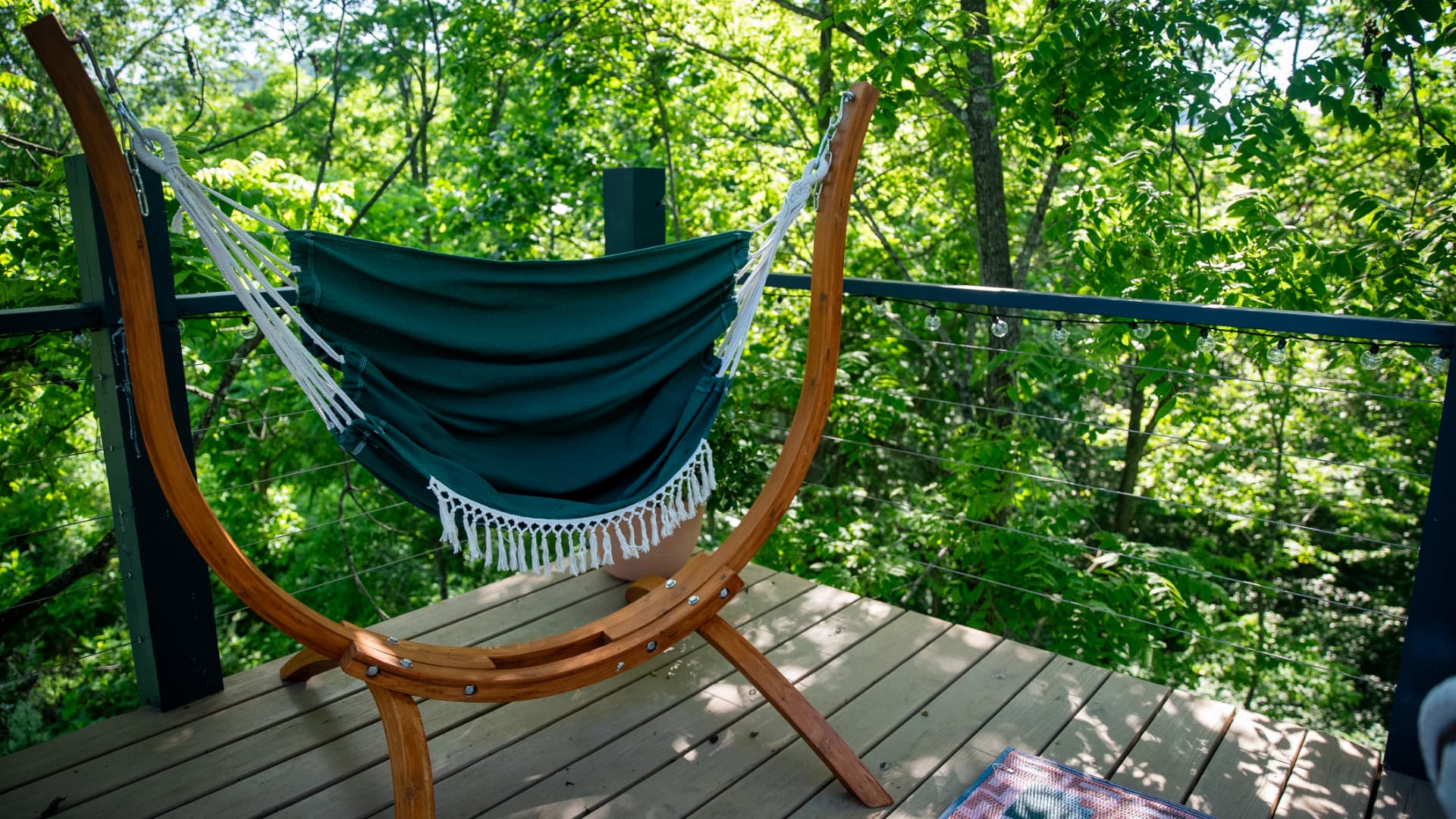 A green hammock chair on the Fes Dome deck, surrounded by trees