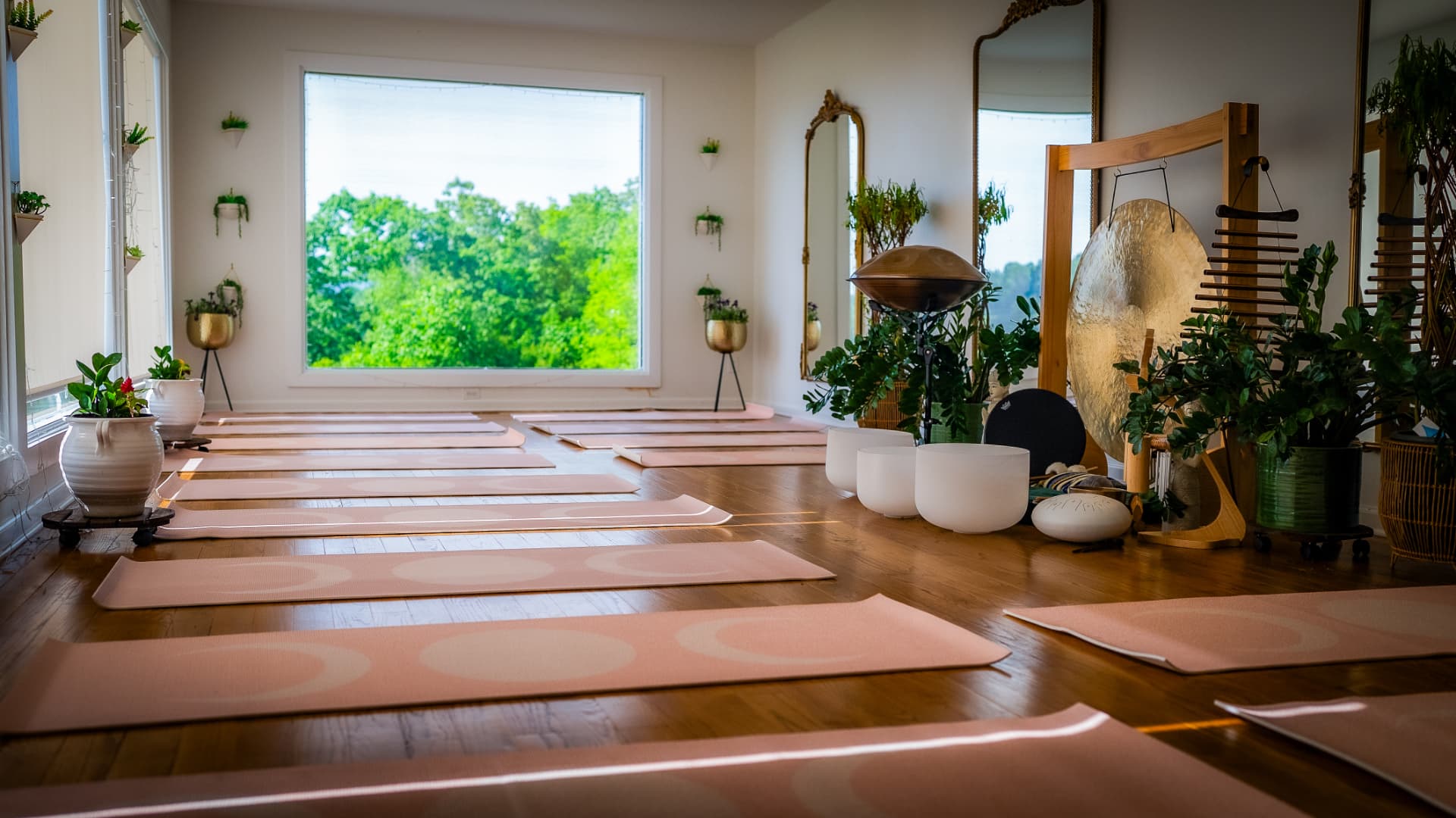 Yoga mats laid out with gong, crystal bowls, and handpan in the glass studio