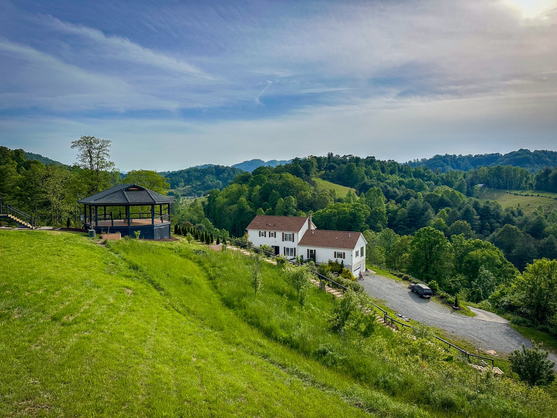 Aerial of the Munaya maison and Sultana pavilion set into the green hillside, valley beyond