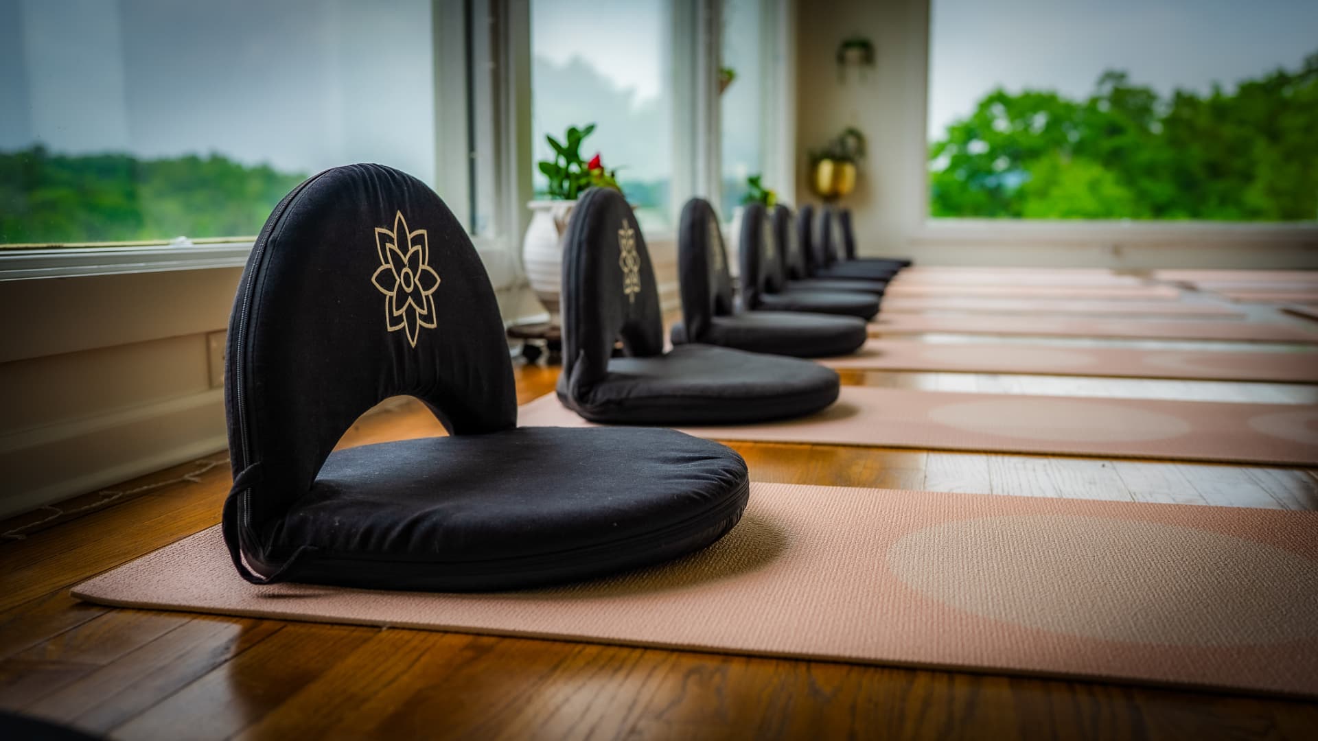 A meditation chair on a mat by the studio windows