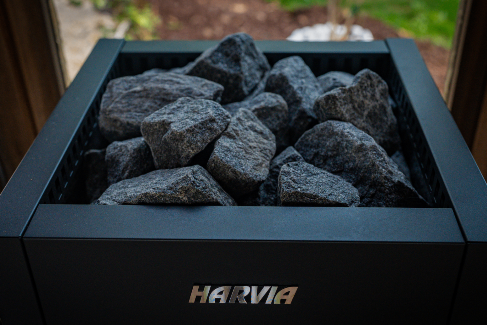Close-up of dark granite stones resting in a black steel Harvia sauna heater