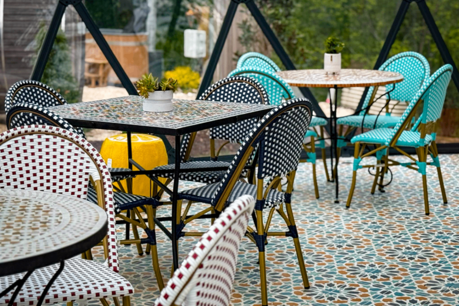 Mosaic tables and colored rattan bistro chairs on a star-patterned tile floor inside the tea house dome