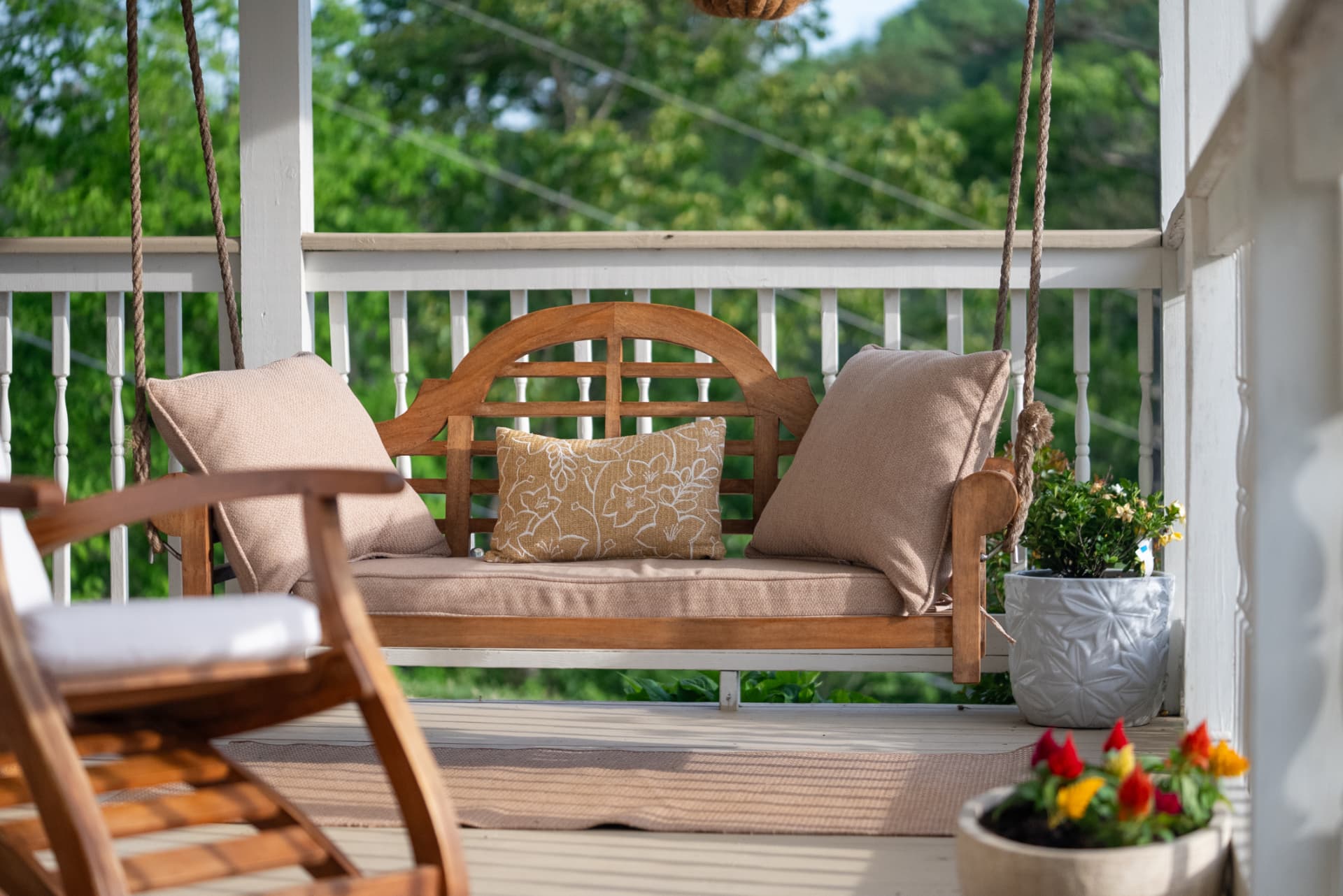 A wooden porch swing with cushions at Munaya Maison