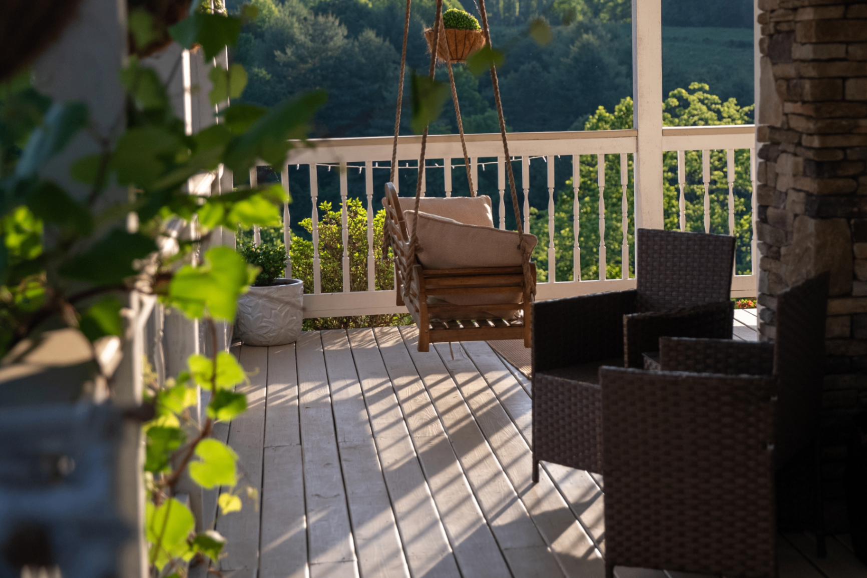 Porch swing at golden hour with vines and stone chimney