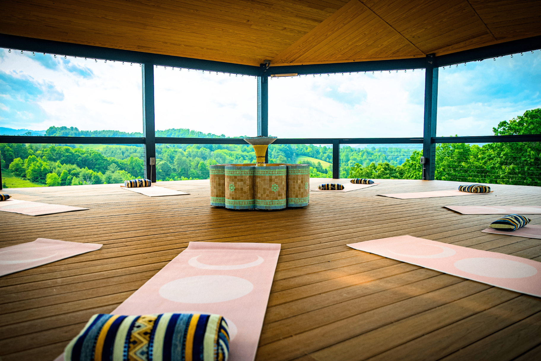 Sultana pavilion set with pink yoga mats and bolsters, mosaic fountain center stage, Blue Ridge mountains beyond