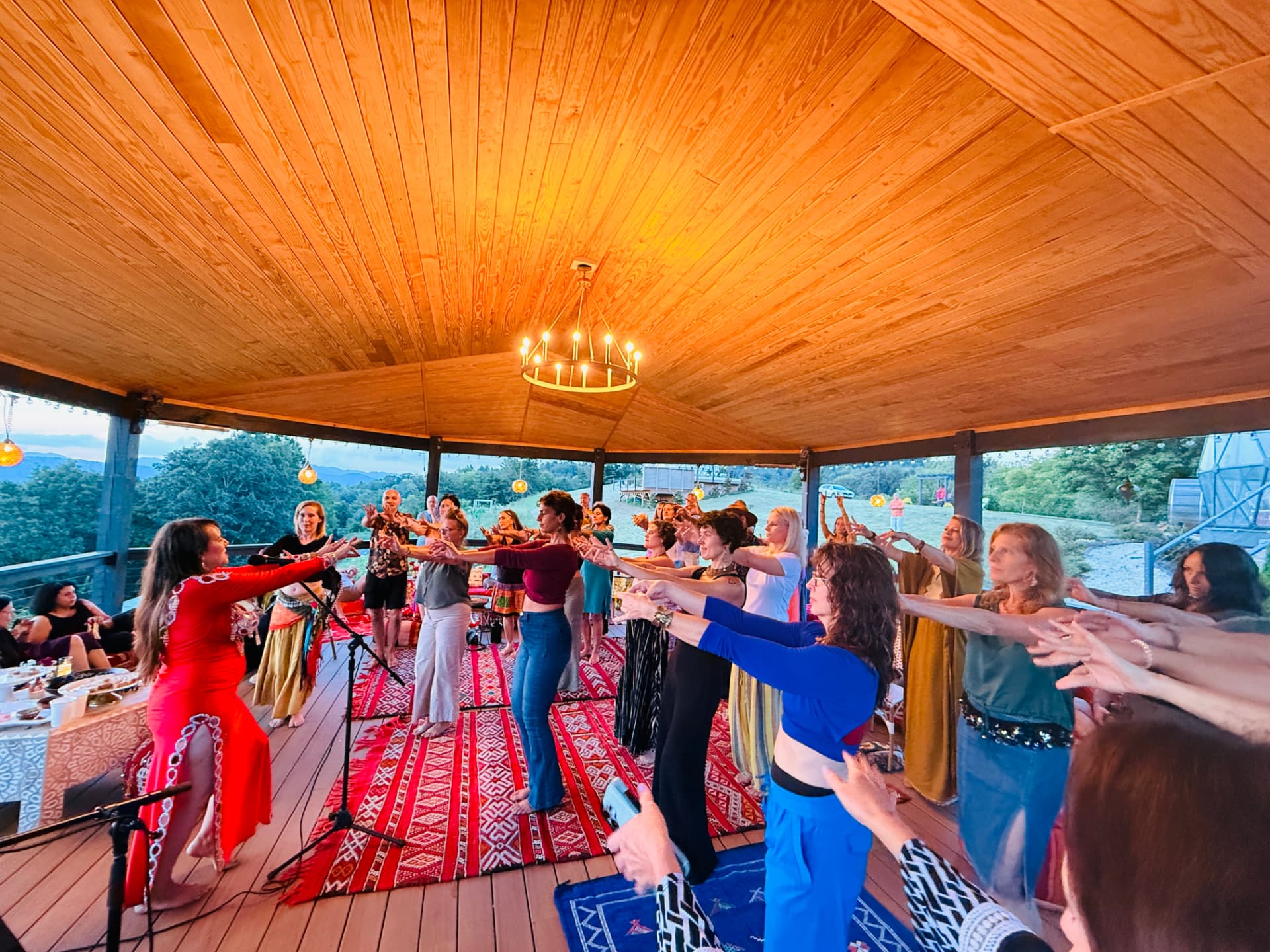 Guests learning belly dance in the lantern-lit pavilion at sunset