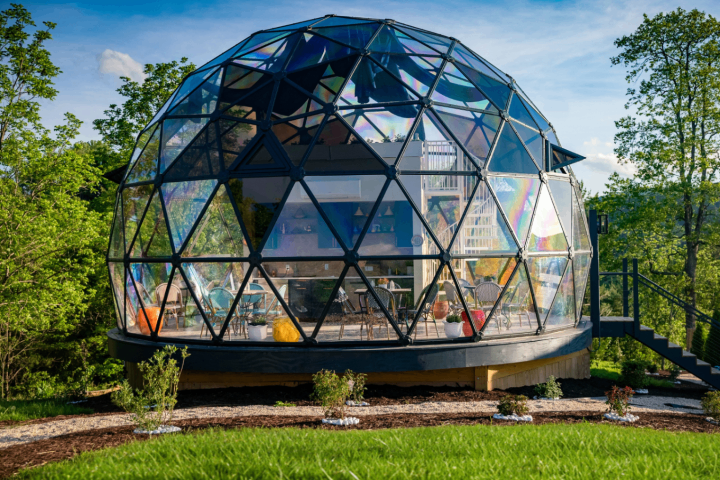 The fully glass geodesic Medina Tea House catching rainbow light, bistro chairs visible inside